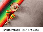 Small photo of Cinco de Mayo holiday background made from maracas, mexican blanket stripes or poncho serape and hat on dark stone background.
