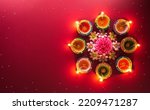 Small photo of Happy Diwali - Clay Diya lamps lit during Diwali, Hindu festival of lights celebration. Colorful traditional oil lamp diya on red background
