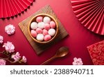 Small photo of Tang Yuan(sweet dumplings balls), a traditional cuisine for Mid-autumn, Dongzhi (winter solstice ) and Chinese new year with plum flower and tea on red background.