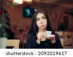 Small photo of Funny Girlfriend Holding a Cup of Coffee Waiting in the Restaurant. Unhappy girlfriend waiting for her date feeling awkward and impatient