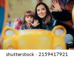 
Happy Mom and Daughter Waving from a Carrousel in a Funfair. Cheerful mother and child having fun rising a merry go round
 
