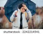 
Woman Holding Her Umbrella Walking into a Windstorm. Unhappy person struggling in a storm fighting strong wind
