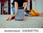 Small photo of Woman Dropping her Phone on the Floor Breaking the Display. Stressed person picking up the broken smartphone she dropped