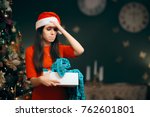 Small photo of Upset Girl Opening a Bad Christmas Gift Finding Pajamas Inside. Funny picky woman disappointed in her unoriginal underwhelming Xmas present