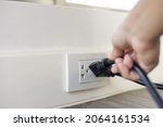 Small photo of In the hand of a young man holding a power cord to unplug unused appliances to save energy, save money.