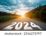 Small photo of New year 2024 concept. Text 2024 written on the road in the middle of asphalt road with at sunset. Concept of planning, goal, challenge, new year resolution.