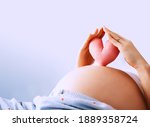 Pregnant woman holds in palms symbol in heart shape. Loving mom waiting of a baby. Concept of maternity, parenting, prepare and expect. Happy expectant mother during pregnancy.