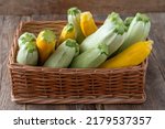 Small photo of Multi-colored zucchini yellow, green, white, orange on the wooden table close-up. Food background. Fresh harvested courgette in basket, cropped summer squash. Picked green courgettes.