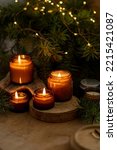 Small photo of Soy candles burn in glass jars. Comfort at home. Candle in a brown jar. Scent and light. Scented handmade candle. Aroma therapy. Christmas tree and winter mood. Cozy home decor. Festive decoration.