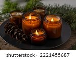 Small photo of Soy candles burn in glass jars. Comfort at home. Candle in a brown jar. Scent and light. Scented handmade candle. Aroma therapy. Christmas tree and winter mood. Cozy decor. Festive decoration