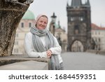 Young brunette woman, standing relaxed on the Charles Bridge walls, over the Vltava river,  Prague City, in Czech Republic.
