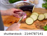 Small photo of women's hands cut eggplant with knife on wooden Board, process of cooking moussaka, ratatouille