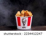 Small photo of Minsk, Belarus - December 03, 2021: black background, night. Lots of hot wings or strips of KFC chicken in a KFC Kentucky Fried Chicken fast food bucket