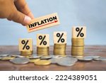 Small photo of Inflation word on wooden block with percentage icon print on stack of coin. Businessman holding block with word Inflation. Concept of high inflation rate increase.
