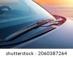 Brushes on the windshield of the car against the backdrop of soft rays of the sun, sunset. Concept for cleaning products, polishing, anti-rain