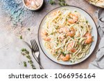 Italian pasta fettuccine in a creamy sauce with shrimp on a plate, top view
