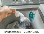man pouring washing powder into the washing machine tank