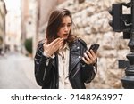 Small photo of Explain wtf message mean. Portrait of frustrated questioned and annoyed young woman arguing over bad news shrugging spread hands in dismay sideways being displeased walking on the street in city.