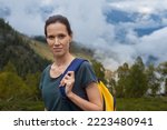 Young caucasian woman hiking in mountains with backpack, enjoying her adventure. Wide shot
