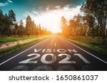 Vision 2021 written on highway road in the middle of empty asphalt road at golden sunset and beautiful blue sky. Concept for new year 2021.