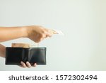 Small photo of Close-up image of a hand holding a leather short wallet with EURO money in it; and another hand bring forward 50 euro banknote to pay for something on white background with copy space.