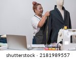 Small photo of Asian tailor creates a pattern using a tape measure for a jacket-style mannequin to tailor suits for customers at her own tailor. Small Business Owner and Designer Tailor concept.