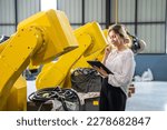 female worker takes note of the number of robotic arms in the factory.