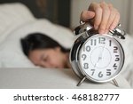 Young woman turns off the alarm clock waking up in the morning.