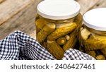 Small photo of Glass jars with pickled red bell peppers and pickled cucumbers (pickles) isolated. Jars with variety of pickled vegetables. Preserved food concept in a rustic composition.