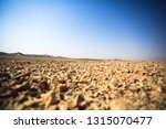 View of the desert with hills in the distance. The horizon is overwhelmed and, according to the first plan, misfocusing stones. Without people. Beautiful blue sky