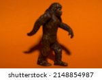 Small photo of Blurry Bigfoot running across a vibrant orange construction paper background