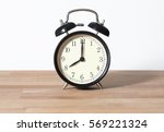 Small photo of It is eight o'clock. The time is 8:00 am or pm. A retro clock isolated on wooden table. White background. Copy space and cut. Copy space and cut.