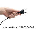Small photo of Electric plug for a socket in a hand on a white background. The concept of electricity and its importance in everyday life. Electric plug without a socket in a human hand. Power plug for the device
