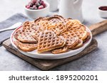 Freshly baked homemade heart shaped Belgium waffles  on gray background. European baked pastry sweets.  St. Valentine's Day breakfast concept.