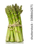 Small photo of Bundle of fresh green asparagus shoots, upright standing. Sparrow grass. Cultivated Asparagus officinalis. Spring vegetable with thick stems and closed buds. Food photo close up front view over white.