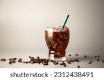 Small photo of Iced americano coffee with coffee beans on grey background, Glass of black coffee, Beverage at coffee shop.