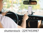 A man drives a car using a GPS navigation system on his mobile phone while driving, to find his destination. Transportation with technology concept.
