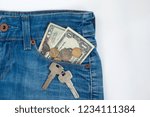 Small photo of Ready money and keys to the house on a keychain are lying in a side pocket of blue jeans.
