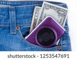 Small photo of Unknown compact camera and ready money are lying in the side pocket of blue jeans.