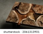 Small photo of Expensive vintage furniture. The table is covered with epoxy resin and varnished. Luxury quality wood processing. Wooden table on a dark background. A gold epoxy river in a rectangular tree slab.