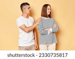 Small photo of Can we try to make peace? Young boyfriend husband touching shoulders of offended girlfriend wife proposing to make peace, reconcile after quarrel isolated over beige background.