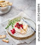 Small photo of French cuisine. Baked camembert cheese with cranberries and thyme. Beautiful serving of an aperitif. Serving snacks on a light background. Serving brie cheese with berries and crackers