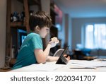 Healthy boy eating red apple for his snack after finished homework,New normal life kid using tablet for home learning,E-learning, Home schooling education, Back to school concept