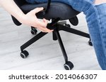 Man checks lifting mechanism of chair. Assembling office chair indoors