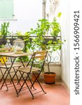 Small photo of An Italian balcony with green potted plants and garden furniture. a table and chairs to enjoy the balmy evening.