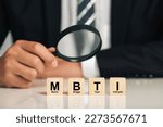 Small photo of businessman holding magnifying glass with wooden cubes with MBTI.Psychological and personality test concept, Personality typology. Psychology test for human types.MBTI - Myers-Briggs Type Indicator
