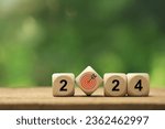 2024 New Year goal plan action. Wooden cubes with 2024 and target icon on a green background. Business plan and development for achieving goals. Goal achievement and success in 2024.copy space 