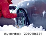 young man with gloves install snow chains in the car tyre in winter on snow