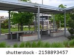 Recreation area with concrete tables and benches on a platform under a metal frame roof. play area, 
