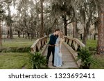 Beautiful Bridesmaid Woman in Blue Dress and Bouquet with Her Date at a Formal Wedding Party Celebration Event Outside in the Woods Taking Couple Portraits on Small Wooden Bridge